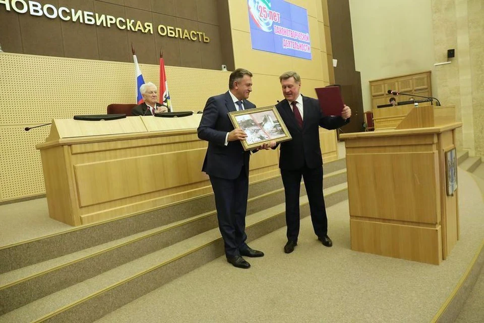 Анатолий Локоть вручает Андрею Шимкиву картину с фотокадром строительства здания Законодательного собрания.