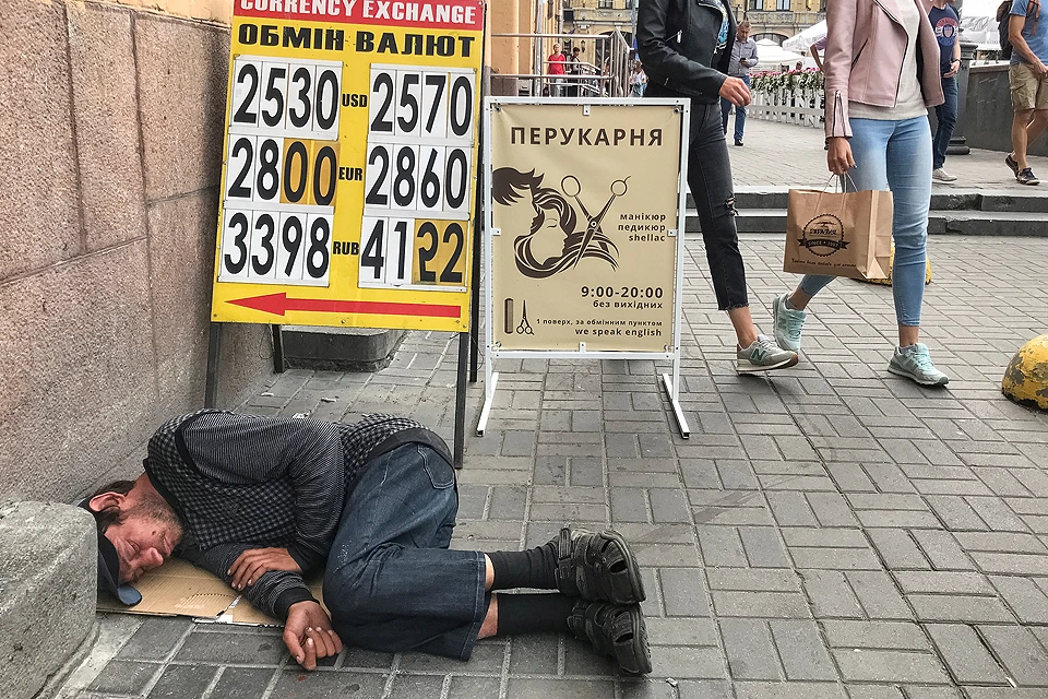 Бездомный спит у пункта обмена валюты в центре Киева.
