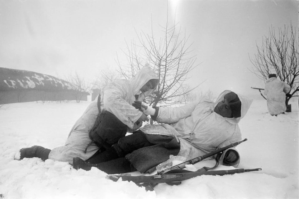 Санитар перевязывает раненого в руку красноармейца во время боя на Юго-Западном фронте.