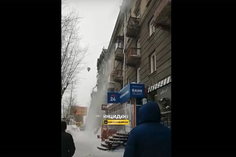 Новосибирцев возмутили рабочие, сбрасывающие снег с крыши дома прямо на прохожих. Фото: Кадр из видео