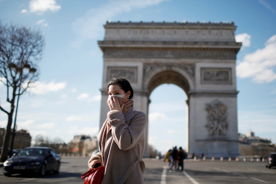 Жительница Парижа проходит в медицинской маске мимо одного из символов города - Триумфальной арки.