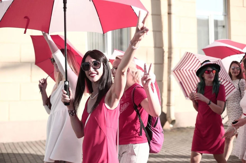 По Минску гуляют девушки с красно-белыми зонтиками.