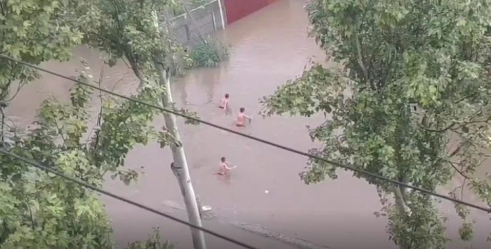 Подростки резвятся в мутной воде, затопившей двор в Керчи. Фото: скрин из видео Анастасии Павлишиной.