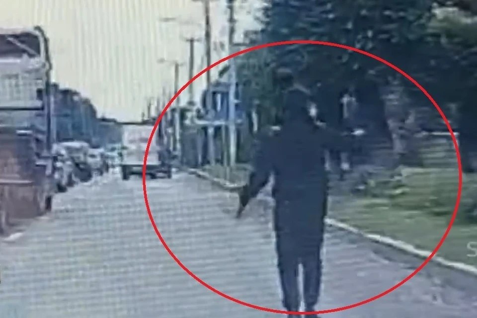 Человек с оружием в руке шл прямо по проезжей части.