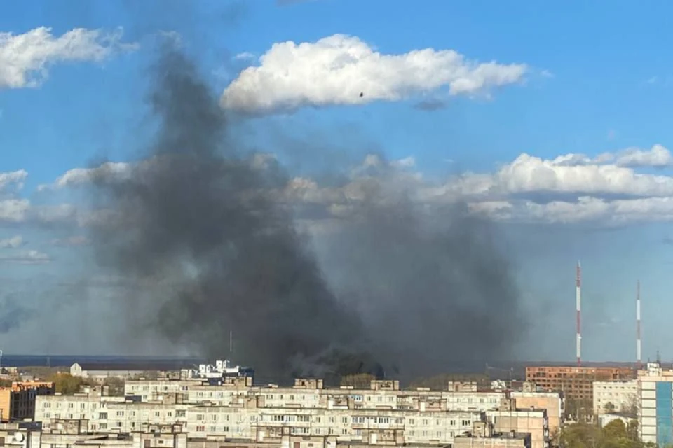 Из-за пожара в небо вздымаются столб черного дыма.