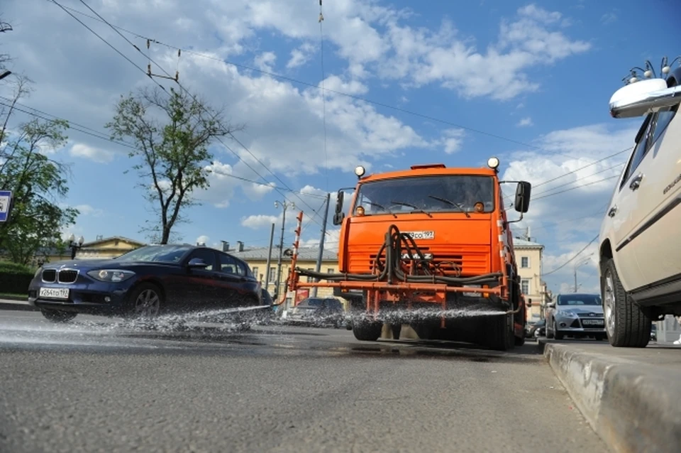 Поливомоечная машина, проходя по дороге, сбивает всю грязь сильной струёй.