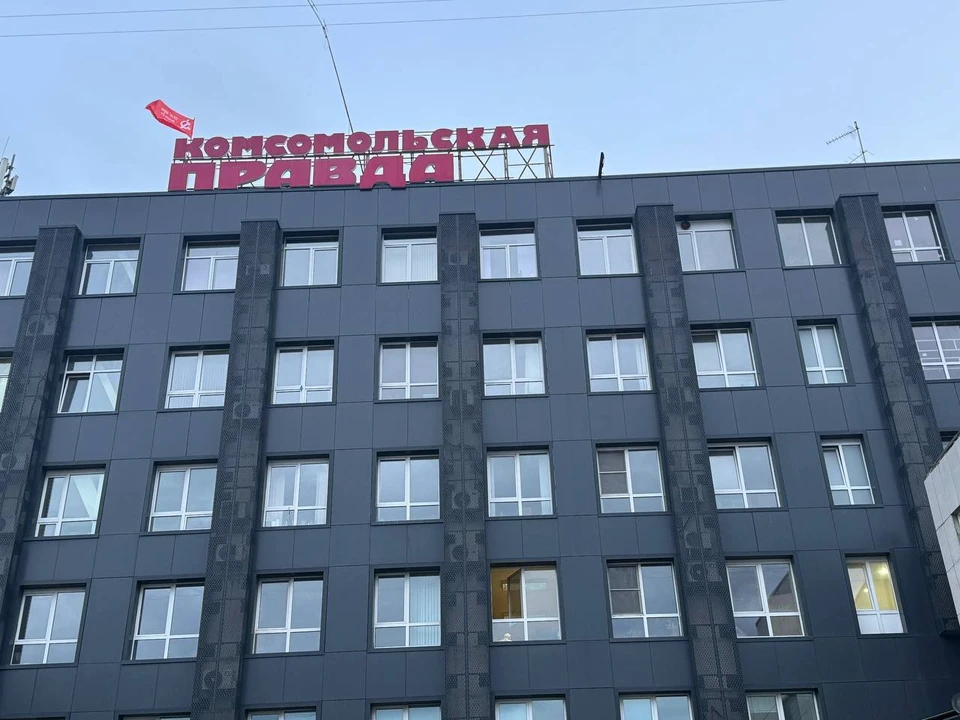 Алый стяг гордо развевается над крышей здания по улице Красной