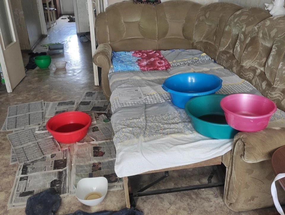 Выстроенные в ряд тазики не спасают жильцов от мокрых потолка и стен, луж на полу и на диване.