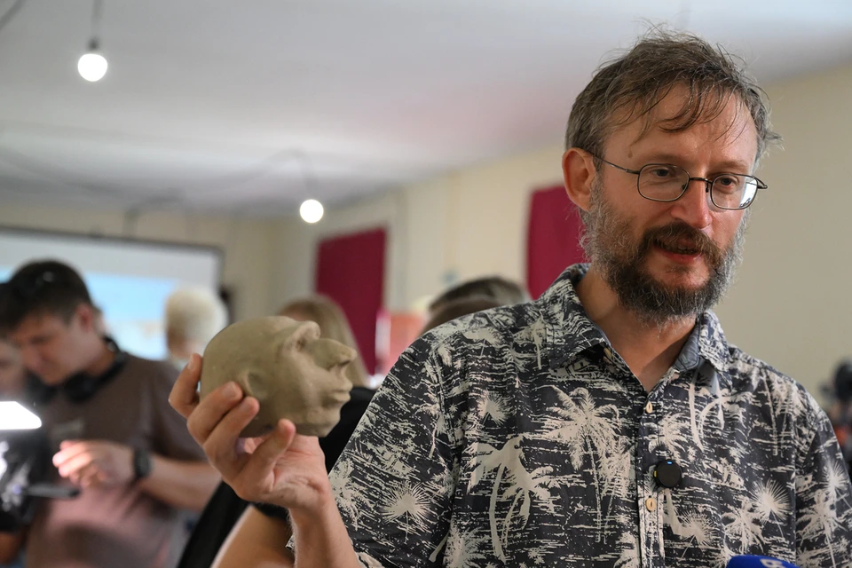 Станислав Дробышевский показывает уменьшенную модель головы неандертальца, сделанную одним из энтузиастов.