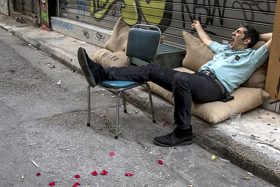 Житель Афин зевает в ожидании разрешения кризиса в отношениях кредиторов Евросоюза и греческих властей.
